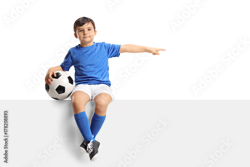 Juliste Little footballer sitting on a panel and pointing