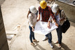 © BalanceFormCreative - Two female inspectors and architects discuss with head engineer about blueprints of construction site.