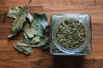 Top View on Glass jar with green dried rosemary on the old wooden table