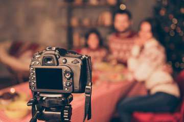 Focused view of gadget, recording brunet famuily celebrate hug embrace bonding smile sitting at the table with dinner at home indoors in traditional x mas noel sweater,s visual not clear view