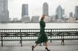 Thoughtful woman walks in her elegant dress along the river shore in New York