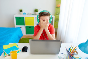 Canvas Print - boy in headphones playing video game on laptop