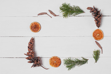 Decoration from pine cones, orange slices and fir branches on the white wooden table. Empty space. Top view.