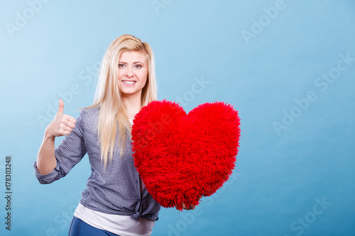 Zdjęcie XXL Szczęśliwa kobieta trzyma czerwoną poduszkę w kształcie serca