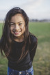 © Rob and Julia Campbell/Stocksy - Cute elementary school aged asian girl happy in windy  field