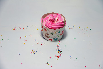 Wall Mural - One birthday cup cake on the white background with colorful rounded sugar beads. cupcake is a small cake baked in a cup-shaped container.