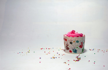 Wall Mural - One birthday cup cake on the white background with colorful rounded sugar beads. cupcake is a small cake baked in a cup-shaped container.