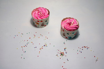 Wall Mural - Two birthday cup cake on the white background with colorful rounded sugar beads. cupcake is a small cake baked in a cup-shaped container.