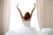 © volha_r - Woman stretching in bed after wake up, back view, entering a day happy and relaxed after good night sleep. Sweet dreams, good morning, new day, weekend, holidays concept