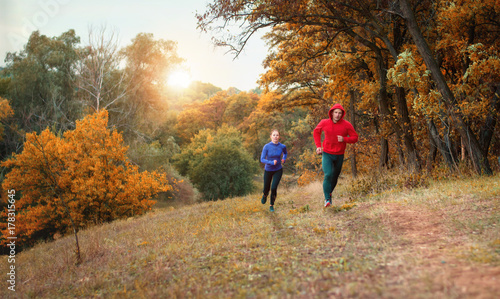 Plakat coupe sportowców w czarnych leginsach i kolorowej kurtce biegnącej po joggingu w kolorowym jesiennym lesie