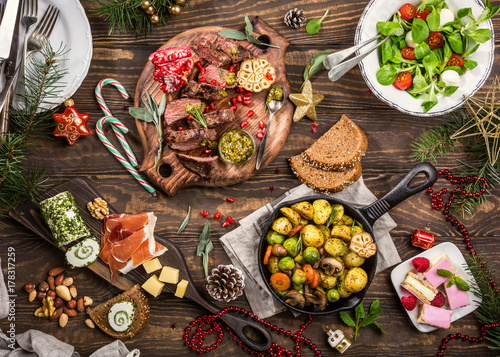 Cuadros en Lienzo Flat lay of Delicious Christmas themed dinner table with roasted meat steak, appetizers and desserts