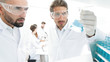 © ASDF - closeup. scientist and assistant studying the solution in the glass tube