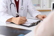 © rogerphoto - Close up of a female doctor filling up  an application form while consulting patient