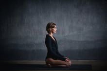 Beautiful Sporty Fit Yogini Woman Practices Yoga Asana Vajrasana - Diamond Pose In The Dark Hall