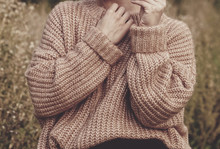Closeup Of Woman Wearing A Beige Soft Oversized Knitted Sweater Or Jumper Outdoors In The Nature. Autumn Fall Scenery