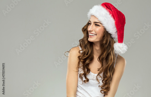 Plakat Piękny uśmiechnięty kobieta model jest ubranym Santa kapelusz