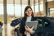© bnenin - Portrait of attractive woman car dealer in showroom.