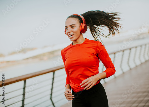 Plakat Aktywna młoda piękna kobieta działa na promenadzie wzdłuż rzeki