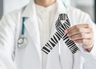 Wall Mural - Carcinoid Cancer Awareness ribbon zebra stripe black and white pattern symbolic bow color on doctor’s hand support