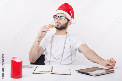 Fotografie, Obraz Young sad and lonely businessman celebrating Christmas in the office drinking champagne at his workplace