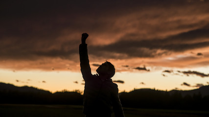 Man raising his fist against sunset sky