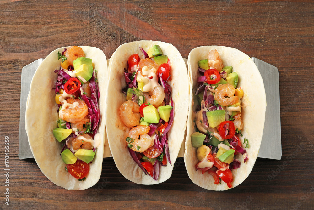 Holder with delicious shrimp tacos on wooden table