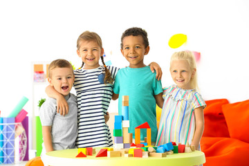 Wall Mural - Cute children playing with blocks on table indoor