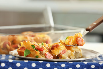 Wall Mural - Fork with delicious sausage casserole over plate, closeup