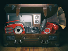 Vintage Suitcase With Old Obsolete Electronic Equipment Set. Retro Technology Concept Background. Radio, Tv Set, Telephone Camera Microphone And Gramophone.