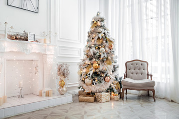 classic white christmas interior with new year tree decorated. fireplace with grey chair, clocks on 