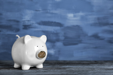 Poster - Cute piggy bank on wooden table against color background