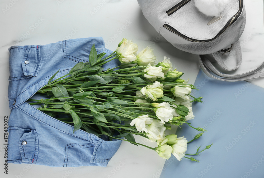 Composition with beautiful flowers in jeans shirt on table