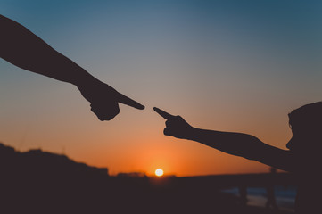 Back side view silhouettes of father holding his child hand over sunset background