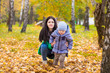 © Svetlana - Mother with little son stands and smiles in park on background of colorful autumn fallen leaves
