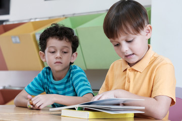 Wall Mural - Two boys studying and reading a book in their classroom, kid education concept