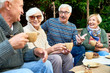 © Seventyfour - Cheerful group of senior friends enjoying each others company while having tea party at lovely patio, they wearing knitted sweaters