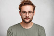© wayhome.studio  - Headshot of serious bearded man with mustache and beard, wears round spectacles, has stylish hairdo, looks confidently, models in white studio, waits for partner. Young student going for classes