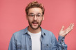© wayhome.studio  - Confused bearded man in denim shirt raises hand with indignation, as discuss something actively, gestures against pink background. Unsure young attractive hipster guy tries to prove his rightness.