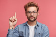 © wayhome.studio  - Funny fashionable man raises fore finger as gets idea, going to speak his mind, isolated over pink background. Male with specific appearance gestures in studio alone, has awkward expression.