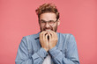© WHstudio Leushin N - Portrait of joyful handsome bearded hipster guy clenches teeth, blinks eye, bites nails, waits to hear something pleasant, recieves compliments or words of praise from boss. Positive facial expression