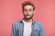 © wayhome.studio  - Good looking male model with stubble presses lips, looks pensively aside, thinks over his future actions or plans, wears spectacles, has clever expression, isolated over pink studio background
