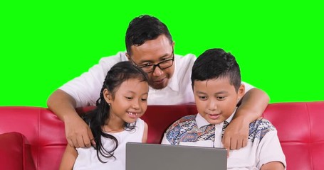Young father prevent his kids watching inappropriate content on internet with a laptop computer by closing their eyes, shot in 4k resolution with green screen background