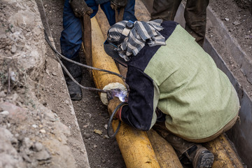 A man welder cooks a pipe at the point of rupture