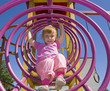 Attractive little girl on outdoor playground equipment