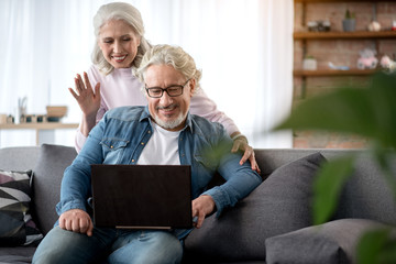 Wall Mural - Cheerful mature husband and wife speaking through internet