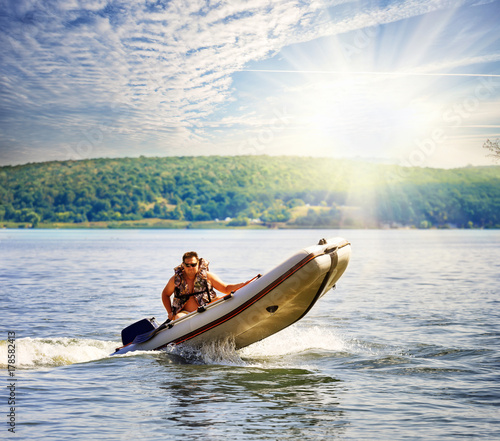 Plakat Nadmuchiwana łódź motorowa z mężczyzną pod jasnym słońcem