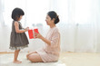 © eggeeggjiew - Asian Little girl and her Mother holding a red gift box together.