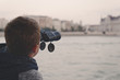 © sakkmesterke - Boy looking by binoculars on cruise trip city