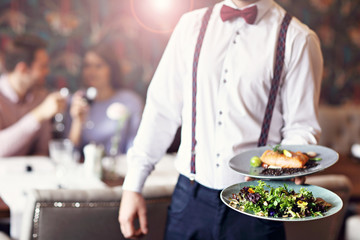 Romantic couple dating in restaurant being served by waiter