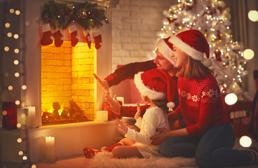 Wall Mural - happy family sitting by fireplace on christmas eve.